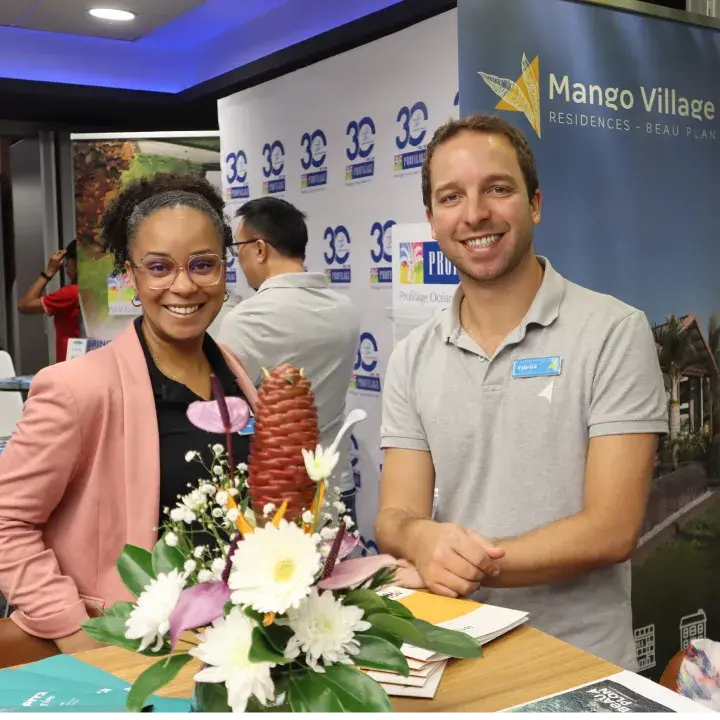 Two smiling Novaterra sales team members at a Mango Village Residences Beau Plan stand with brochures at a property fair