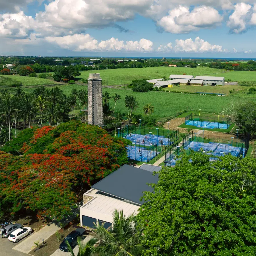 Vue aérienne du quartier Mon Rocher à Beau Plan avec ses courts de padel, une ancienne cheminée sucrière et des champs