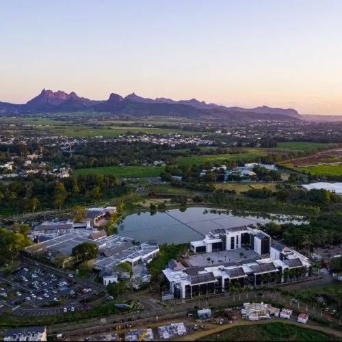 Vue aérienne de Beau Plan Smart City au crépuscule, avec bâtiments modernes, lac, parking et montagnes en arrière-plan