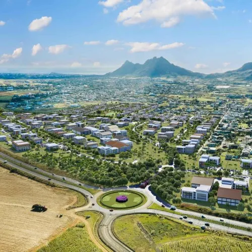 Vue aérienne de Moka Smart City avec immeubles, rond-point fleuri et champs, au pied des montagnes de Moka