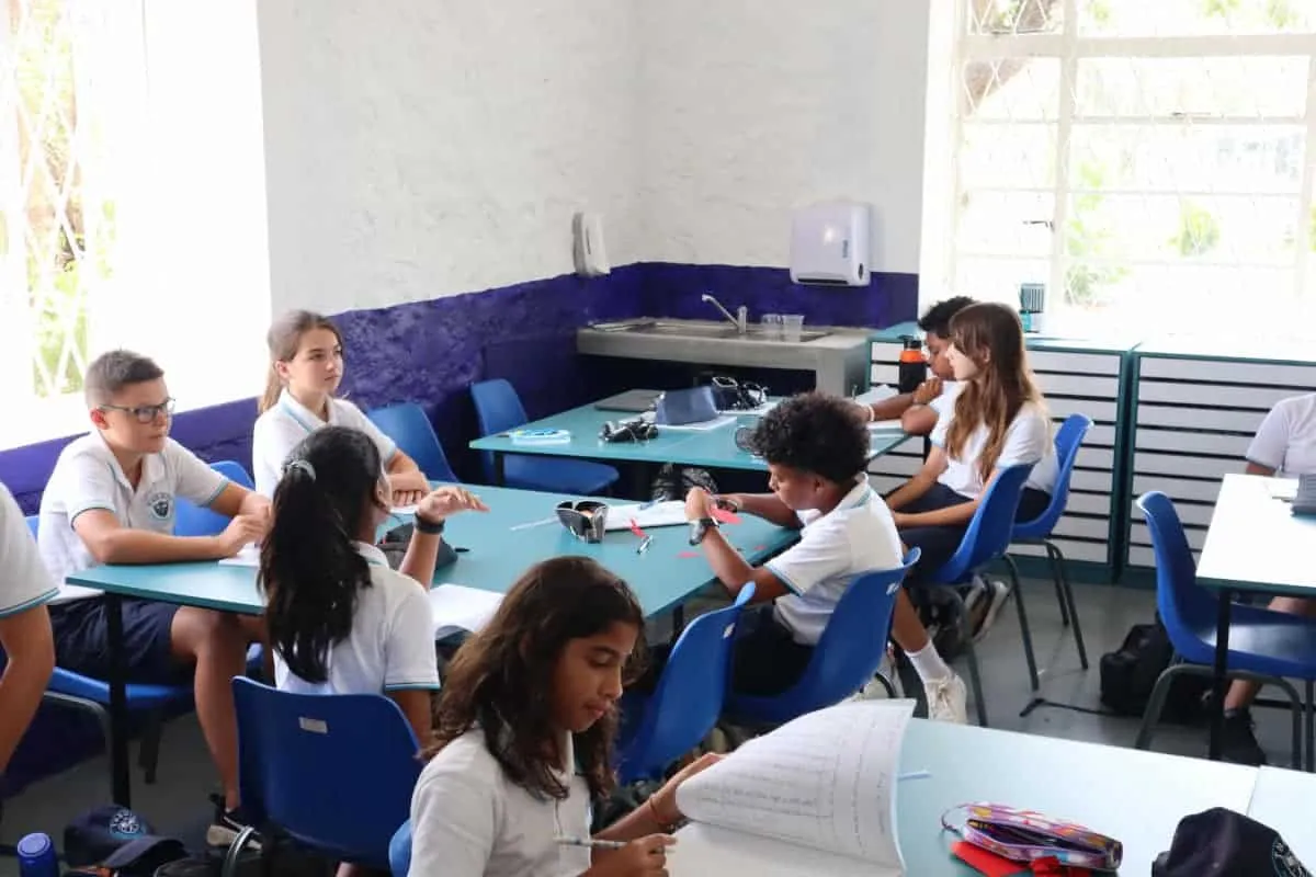 Élèves en uniforme travaillant en groupe dans une salle de classe rénovée de Themis International School à Beau Plan