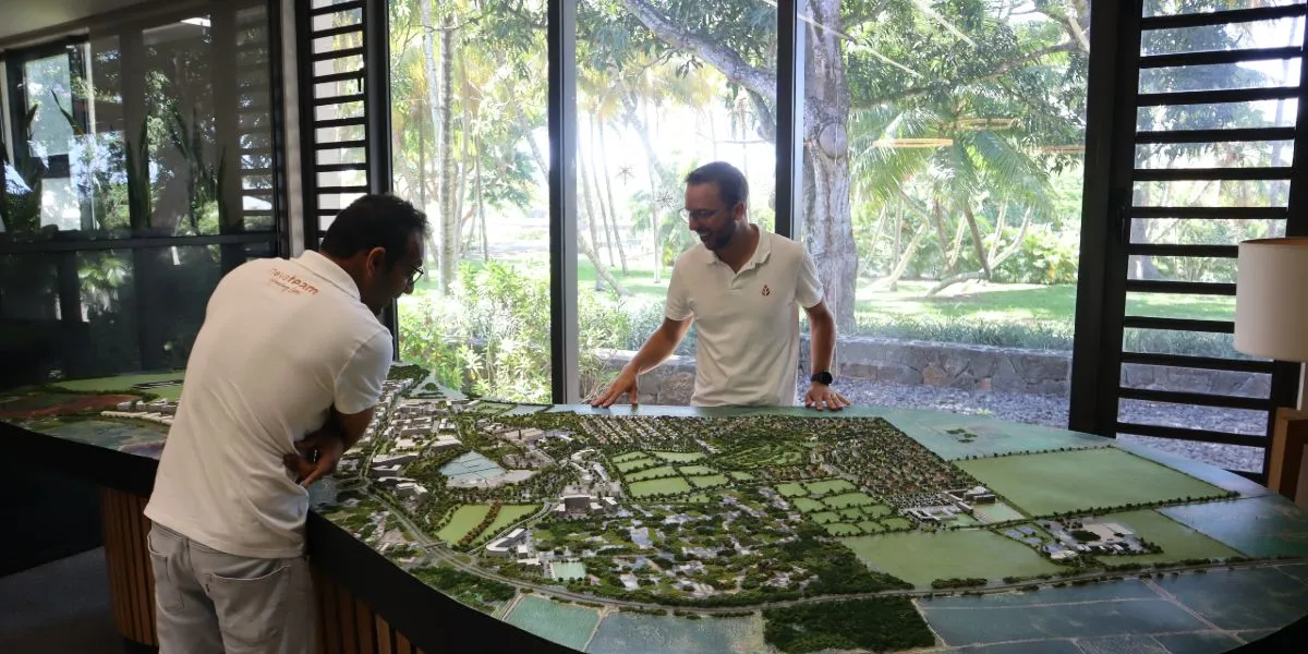Two men in white polo shirts study the nearly 3-metre scale model of Beau Plan in Novaterra's reception area