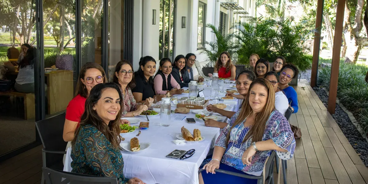 EmpowerHer programme participants, a group of women, smiling around a lunch table on an outdoor terrace
