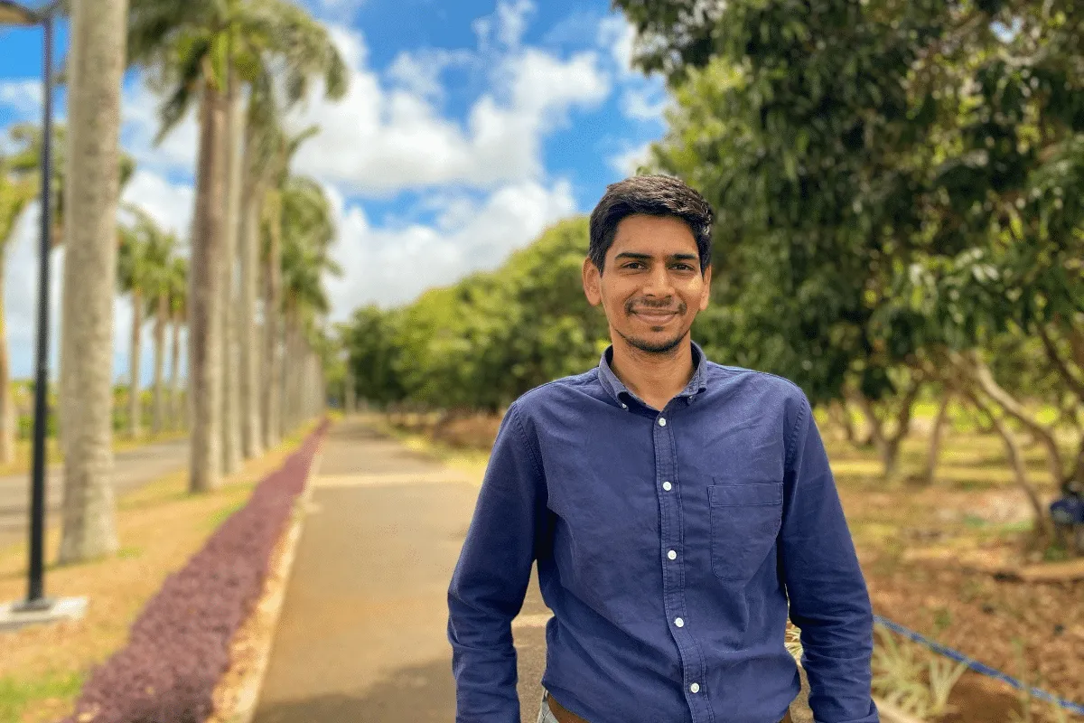 Nawaz Imrit, Development Manager chez Novaterra, souriant en chemise bleue devant une allée bordée de palmiers
