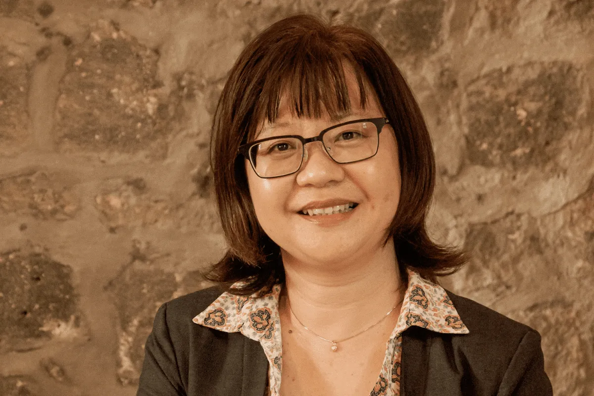 Stephanie Wong, Senior Accountant at Novaterra, smiling in glasses and a dark blazer in front of a stone wall