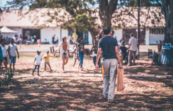 Families and children gather on a shaded lawn before former warehouse buildings at the Creative Park in Beau Plan