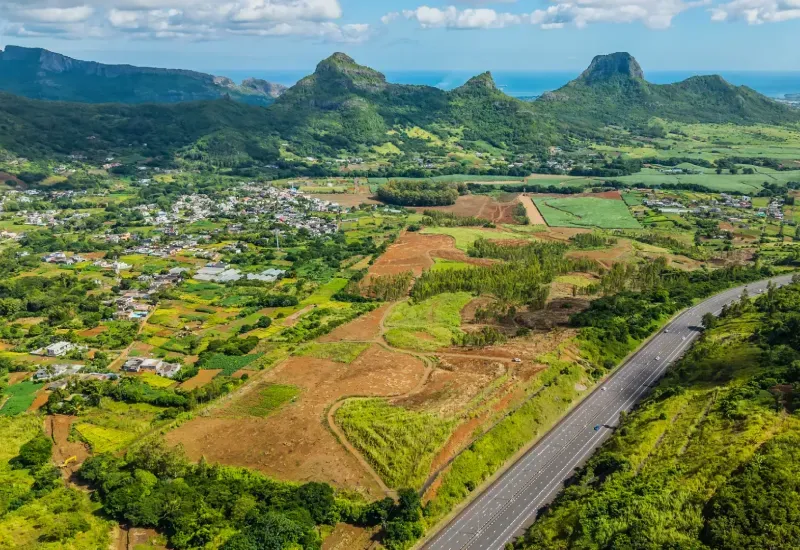 Aerial view of Domaine de Crève-Cœur farmland beside the Terre Rouge–Verdun motorway, with green mountains and the sea beyond