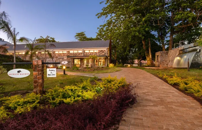 Patrick Mavros jewellery store in a restored stone foundry at Beau Plan, with a brick path and gardens at dusk