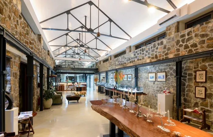 Patrick Mavros jewellery store in a restored Beau Plan foundry, with stone walls, steel roof trusses and a long wooden table