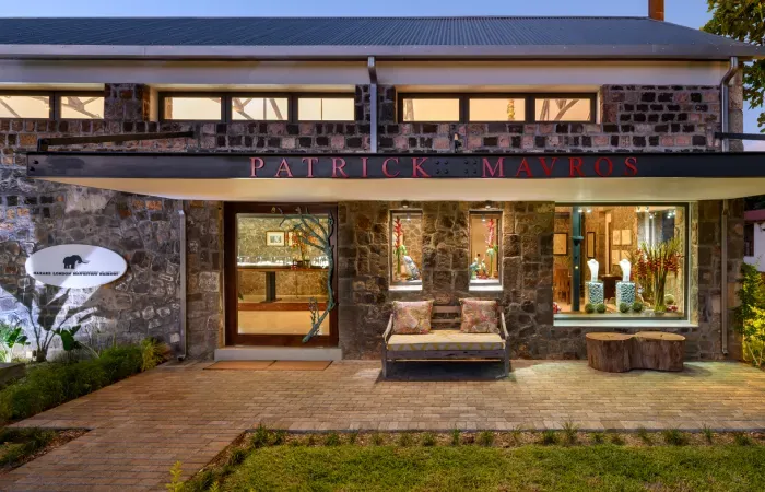 Patrick Mavros jewellery store in a restored stone foundry at Beau Plan, lit at dusk with a bench on the paved terrace