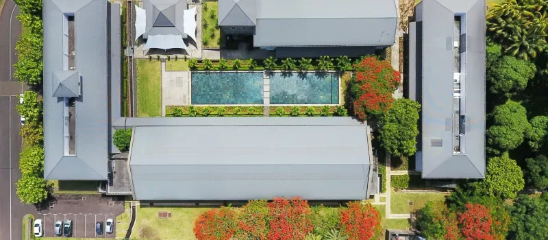 Aerial view of Beau Plan Business Park office buildings around a central pool, bordered by flame trees and greenery