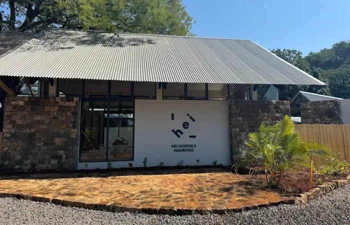 HEI Schools Mauritius building in Forbach, old stone walls under a corrugated metal roof with large windows and palms