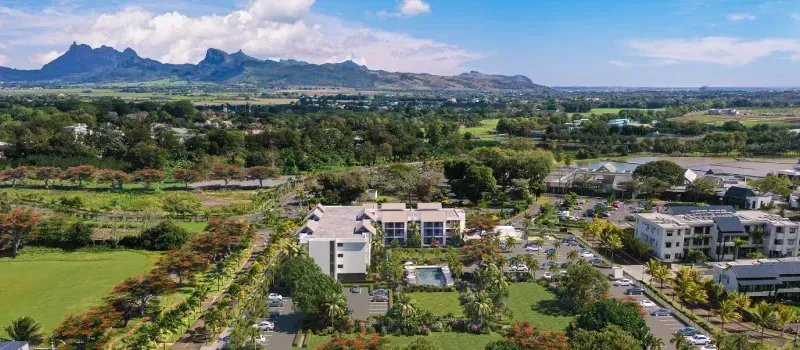 Aerial view of Indigo Phase 1 apartment buildings with a pool in Beau Plan, set among greenery with mountains behind