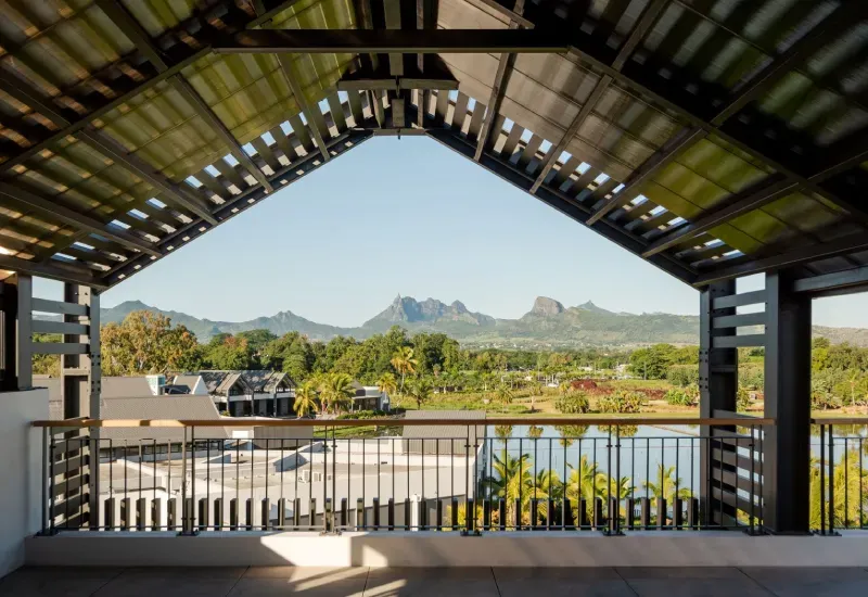 Covered terrace at The Strand offices overlooking a lake, tropical gardens and the Moka mountains under a blue sky