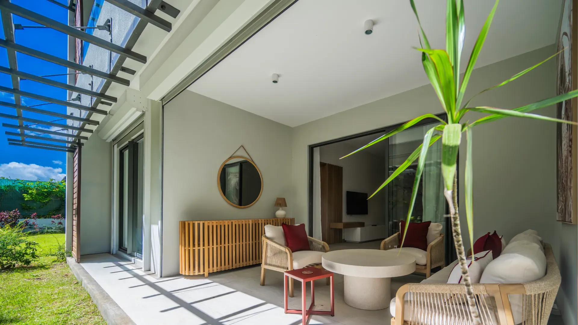 Covered terrace of a 3-bedroom Mango Village apartment with wicker armchairs, round table and garden view