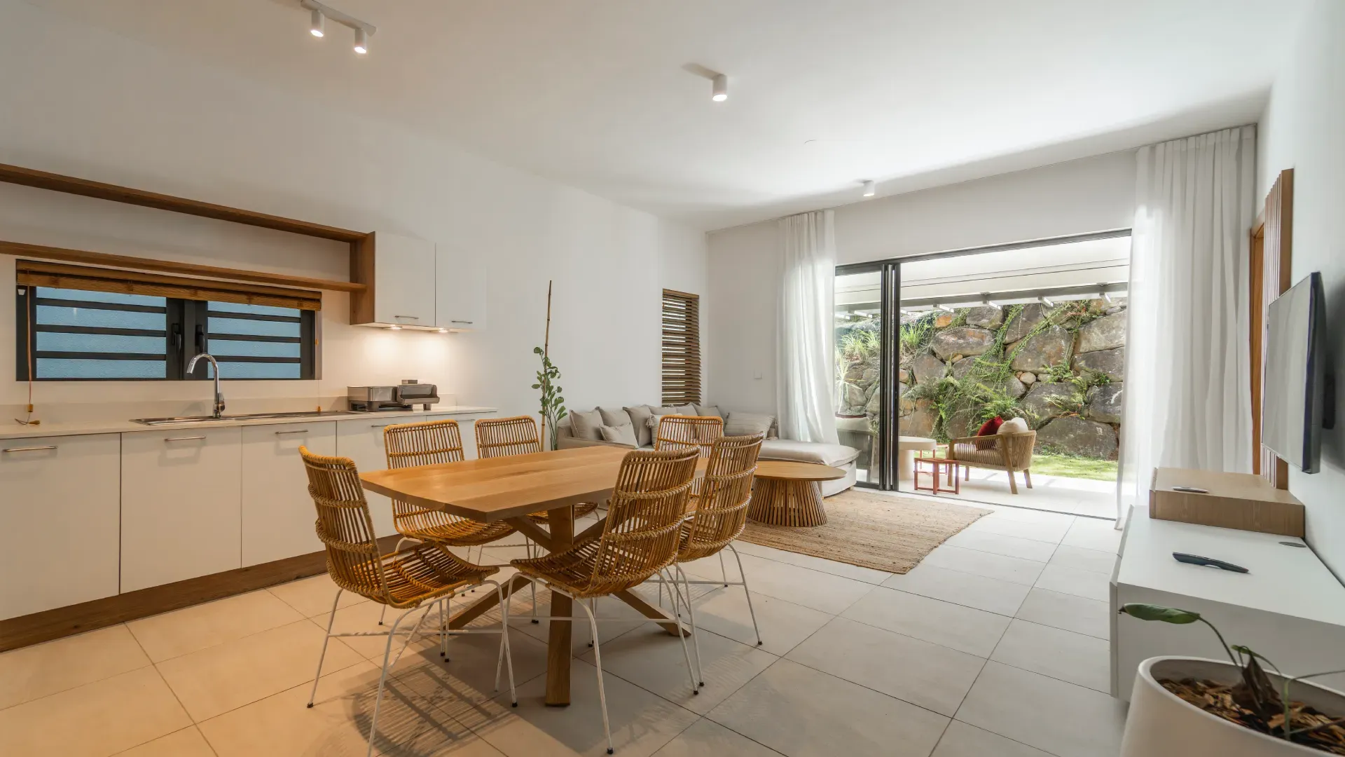 Open-plan kitchen, dining and living area of the 3-bedroom Mango Village apartment, opening onto a garden terrace