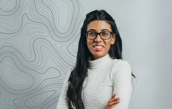 Sanyukta Lutchun, Novaterra Development Lead, smiling with arms crossed in front of a topographic line wall