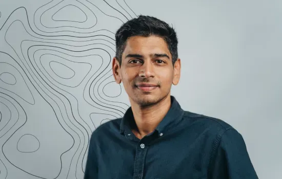 Portrait of Nawaz Imrit, Development Manager at Novaterra, in a dark shirt against a topographic line wall