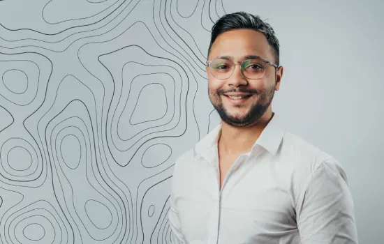 Benoit Vincent, Graphic Designer, smiling in glasses and a white shirt against a wall with contour line patterns