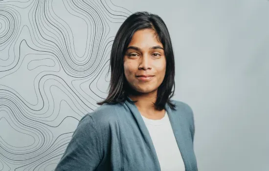 Cheshta Hurnauth, Novaterra Landscaping Lead, smiling in a teal cardigan before a contour-line map backdrop