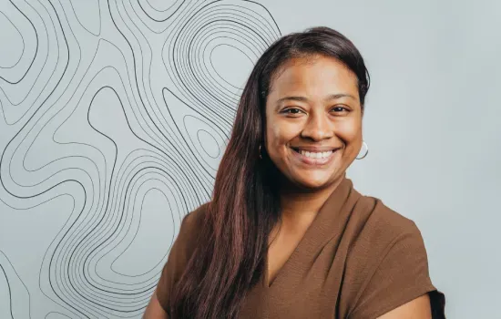 Portrait of Elodie Joson, Sales Administrative Support at Novaterra, smiling in a brown top before a contour-line wall
