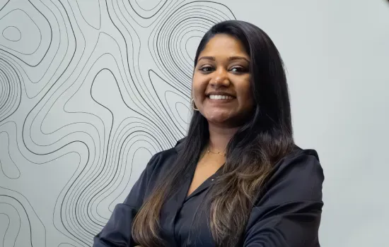 Anisha Inassee, Property Administrator at Novaterra, smiling in a black blouse before a wall with contour-line patterns