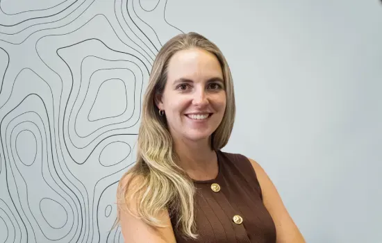 Yasmin Boulle, architect at Novaterra, smiling in a brown sleeveless top before a wall with topographic line art