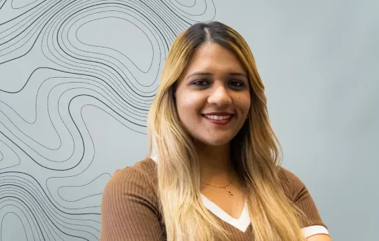 Zohra Chitbauhal, Technical & Administrative Officer at Novaterra, smiling in front of a contour-line wall