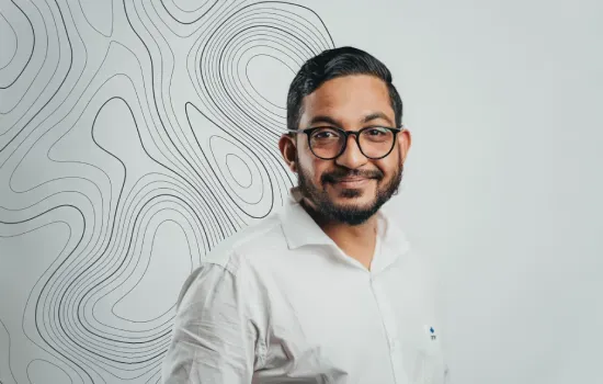 Shameem Khodabocus, Accounts Receivable Officer, smiling in glasses and a white shirt beside a contour-line wall design