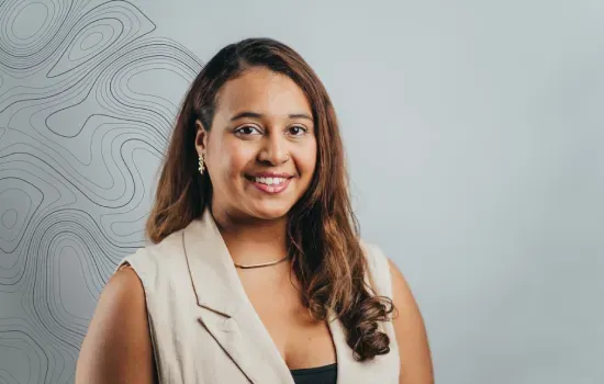 Victoria Monneron, Human Resources Officer at Novaterra, smiling in a beige sleeveless blazer against a grey contour-line backdrop