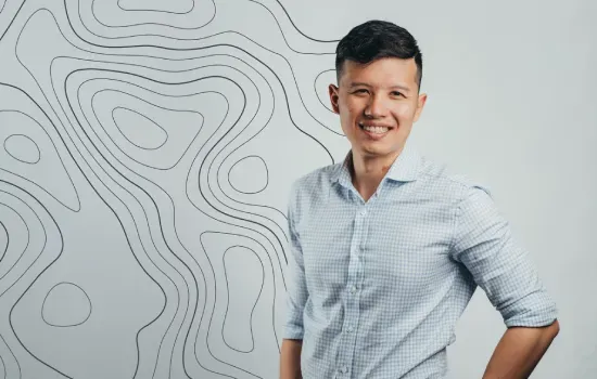 David Cheung Han Sing, Finance Manager, smiling in a light blue shirt before a wall with topographic line patterns