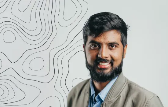 Koushal Pargass, Human Resources Officer at Novaterra, smiling in a khaki jacket before a topographic line backdrop