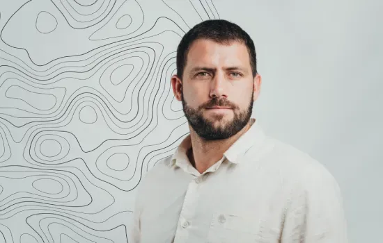 Simon Rey, Facilities Manager, in a white linen shirt against a light backdrop with topographic contour lines