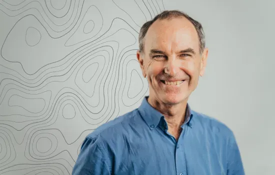 Yves Menage, Leasing Manager at Novaterra, smiling in a blue shirt against a wall with contour line patterns