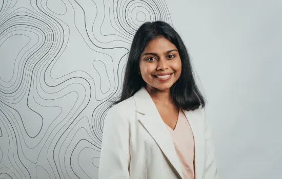 Raksheeta Boodan, Accounts Clerk at Novaterra, smiling in a white blazer before a wall with topographic line art