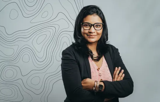 Aurelie Oudin, Accountant at Novaterra, smiling with arms crossed in front of a topographic line pattern backdrop