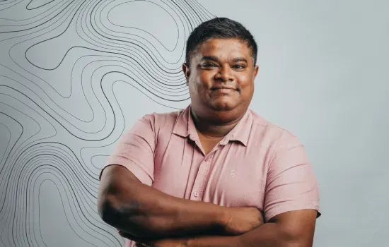 Varun Goorooa, Messenger and Office Attendant at Novaterra, smiling with arms crossed in a pink shirt