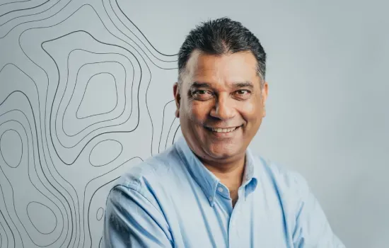 Pravin Hanuman, Senior Development Manager at Novaterra, smiling in a light blue shirt before a contour-line wall