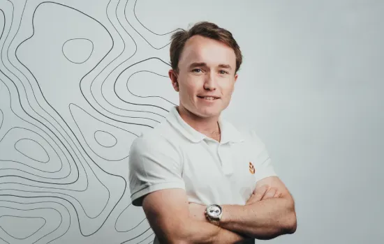 Amaury Chasteau de Balyon, Financial Analyst at Novaterra, arms crossed in a white polo against a contour-line backdrop