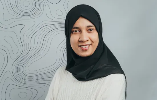 Feiriaza Nohur, Novaterra Property Administrator, smiling in a black hijab and white sweater against a contour-line backdrop