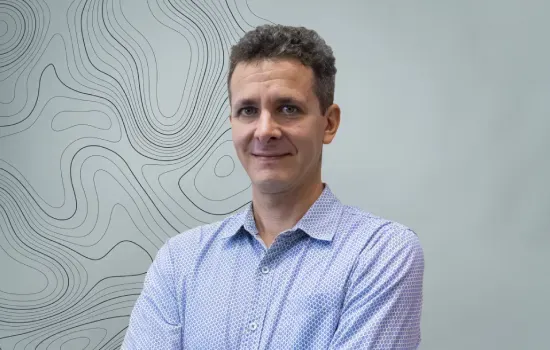 Xavier Harel, Digital and Marketing Executive at Novaterra, in a blue shirt before a contour-line patterned wall