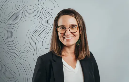 Chloe Langlois, Sales & Leasing Executive at Novaterra, smiling in glasses and a black blazer before a contour-line wall