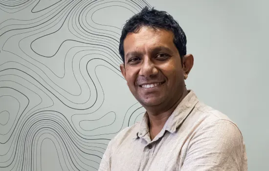 Sivasagam Moorghen, Senior Syndic Officer at Novaterra, smiling in front of a wall with topographic contour lines
