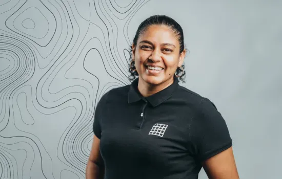 Elvina Inassee, Property Administrator, smiling in a black Novaterra polo shirt against a contour-line backdrop