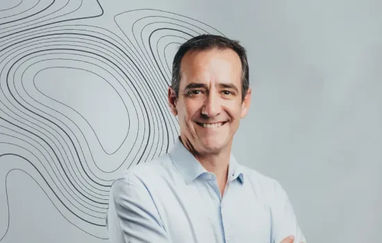 Joel Couve de Murville, Head of Sales and Marketing, smiling in a light blue shirt before a contour-line backdrop