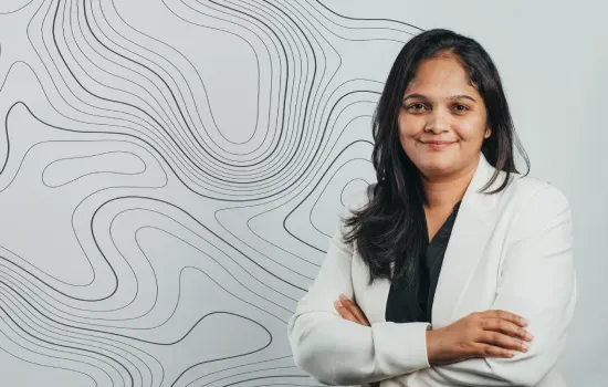 Christel Théodore, Senior Accountant at Novaterra, smiling with arms crossed in a white blazer before a contour-line wall